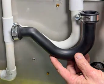 Holding the flexible condensate trap against the existing PVC trap to check the fit