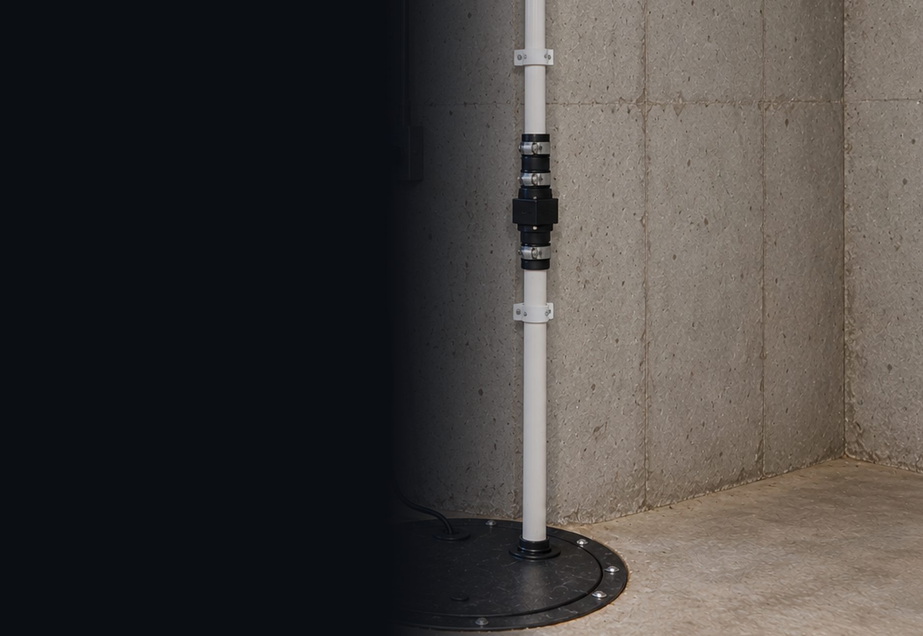 Fernco check valve installed on a white PVC sump pump discharge pipe rising from a sealed sump pit in a basement