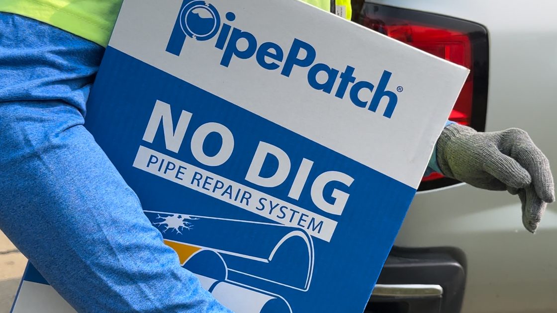 A crew member carrying a PipePatch kit box to the truck
