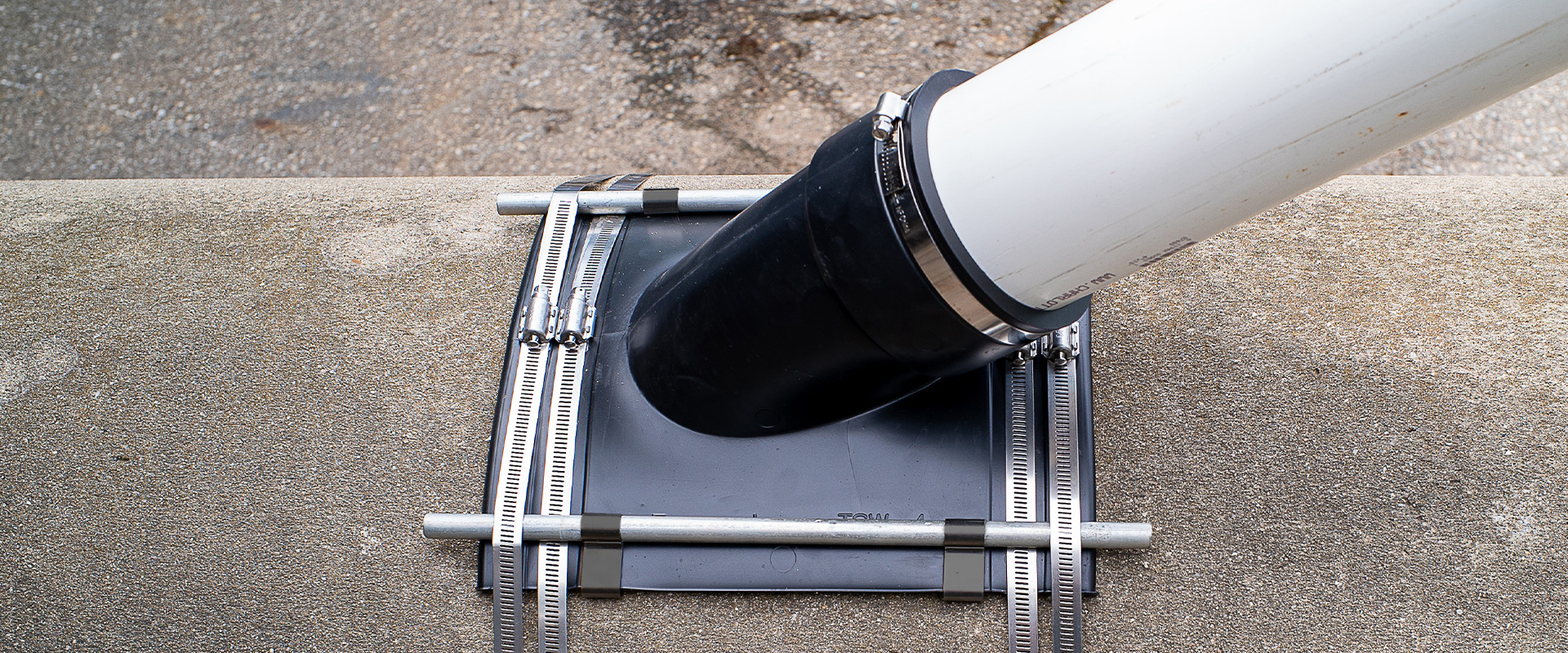 Fernco Flexible Tap Saddle installed on a sewer main with a lateral connection and stainless reinforcing bars