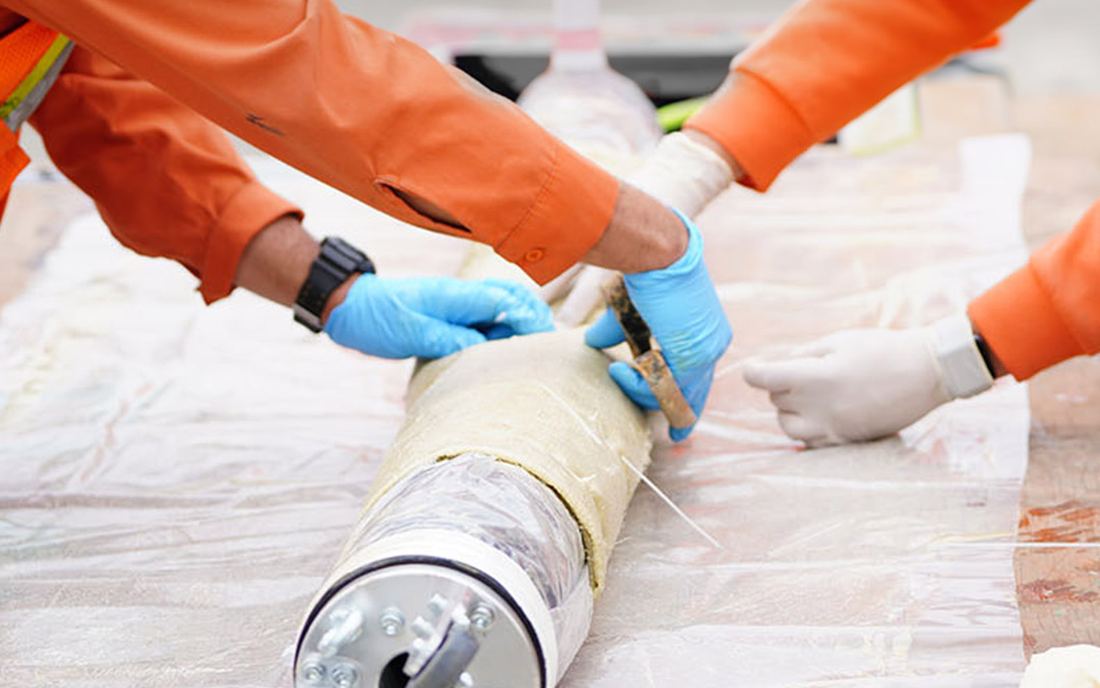 Two crew members tying the resin-soaked patch onto the packer