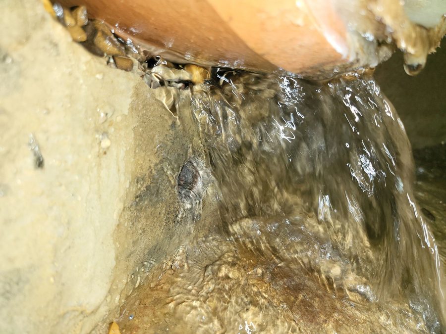 Groundwater pouring into a manhole around a pipe connection