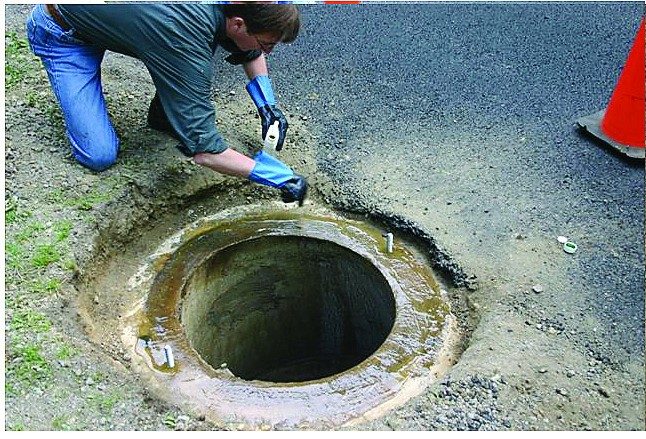 A worker in gloves preparing the top of a manhole before setting a frame