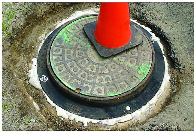 The finished manhole with its cover back in place and a traffic cone on top